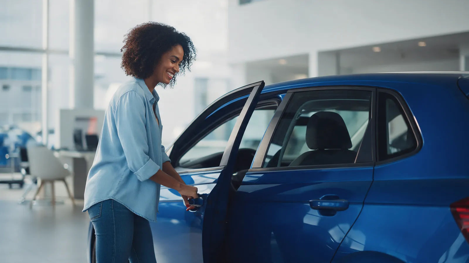 Carta contemplada de veículo: mulher abre a porta de um carro azul na concessionária